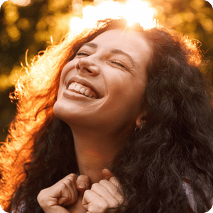 Woman with brown curly hair looking at sky smiling and happy