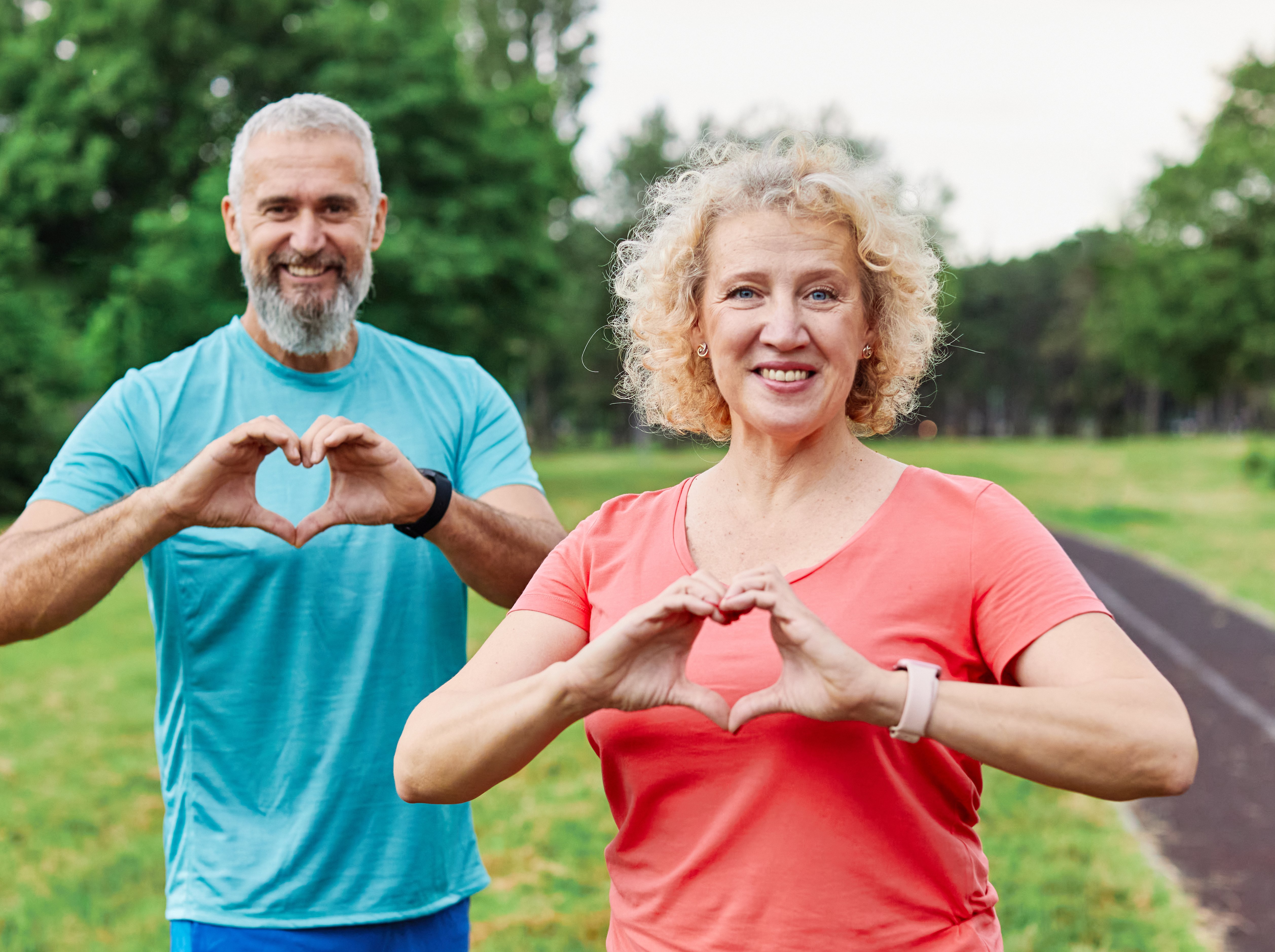 man and woman outside making heart shapes with hands