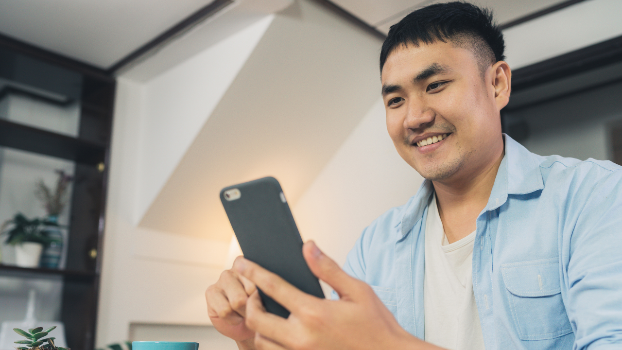 asian man smiling looking at phone