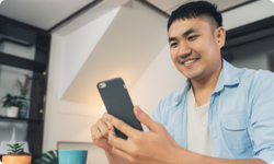 Asian man smiling looking at phone