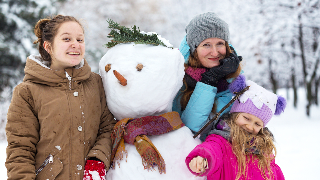 mom and two girls building a snowperson