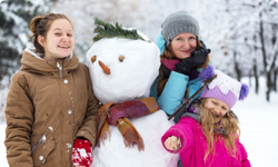 mom and two daughters making a snowperson