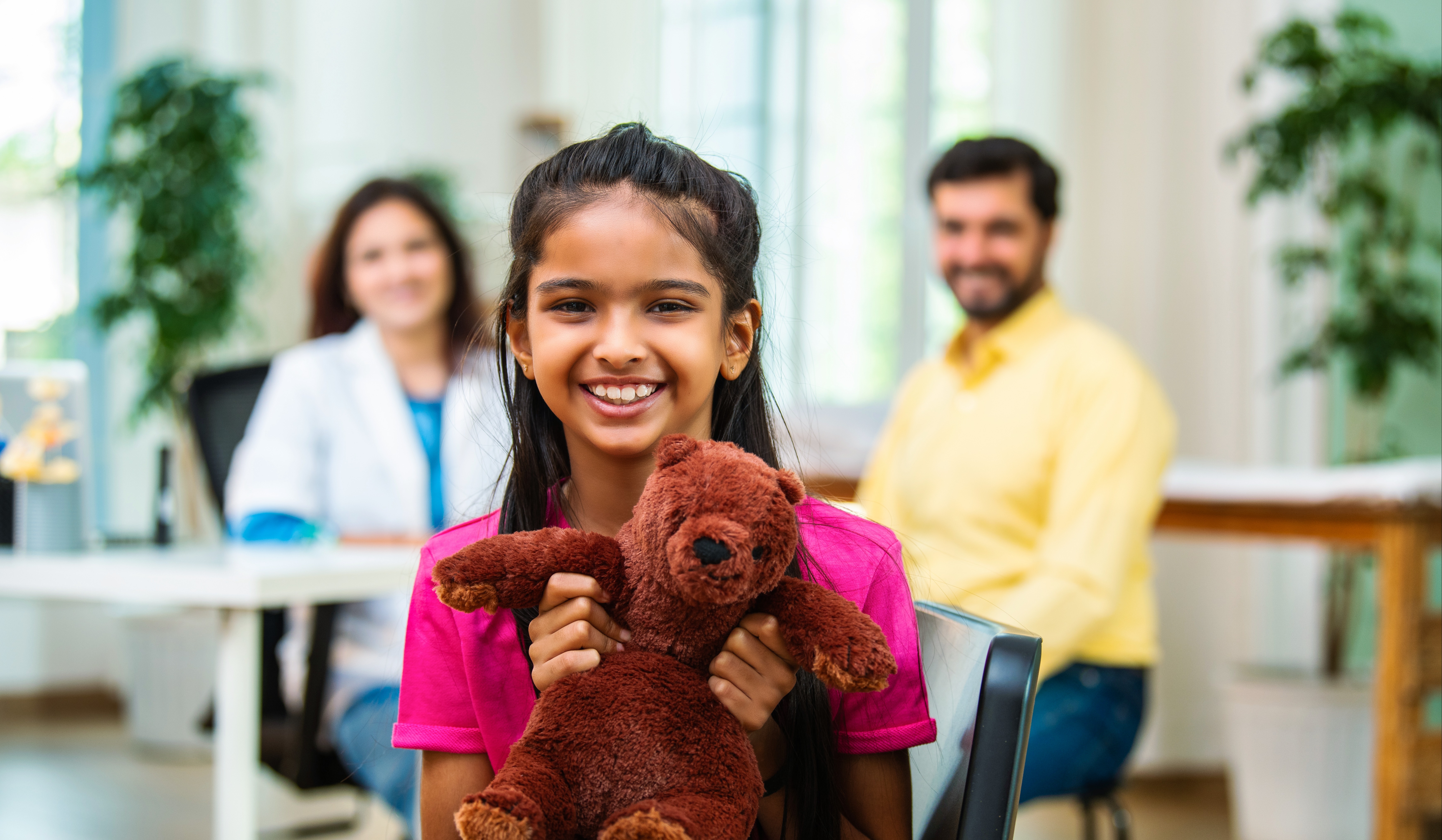child smiling with teddy bear